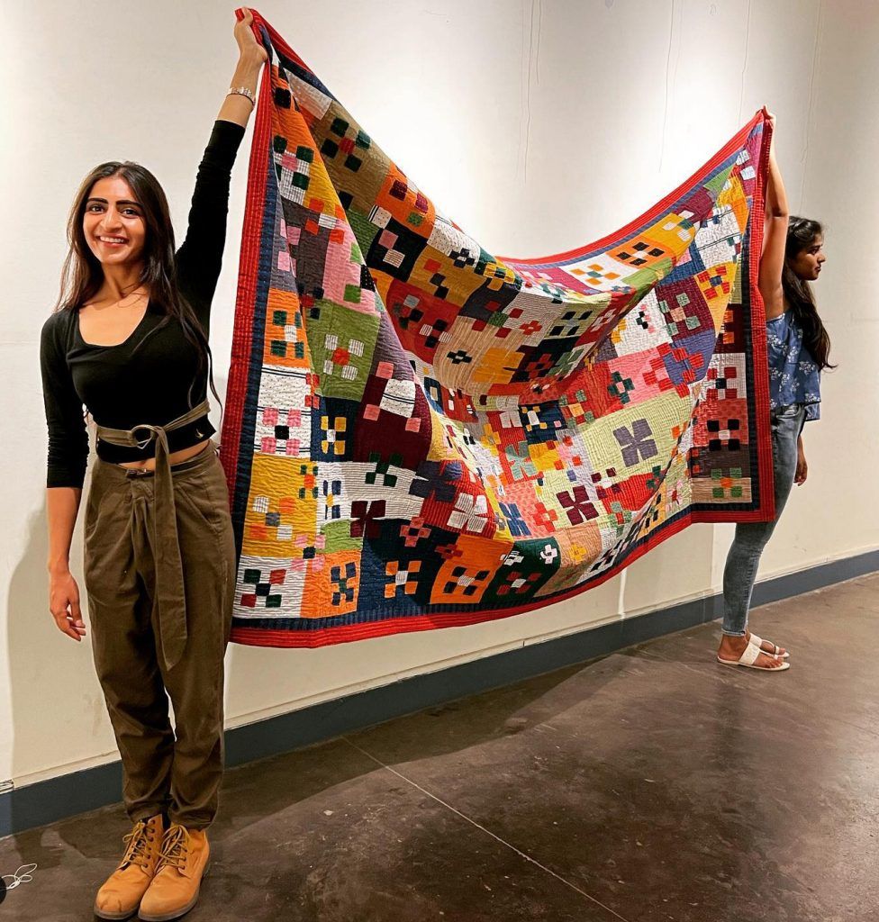 alt= Le Gist photo two woemen holding sidddi quilt, at exhibition